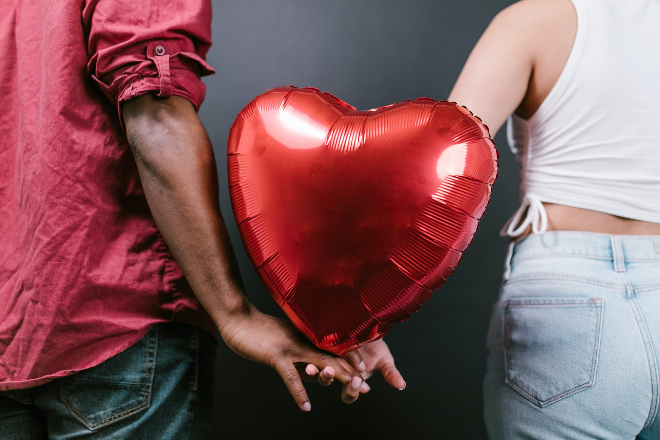 man and woman holding a red balloon